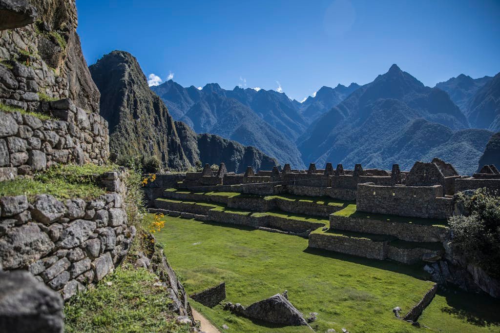 Breathtaking view of Machu Picchu ruins surrounded by the Andes mountains under a clear blue sky.