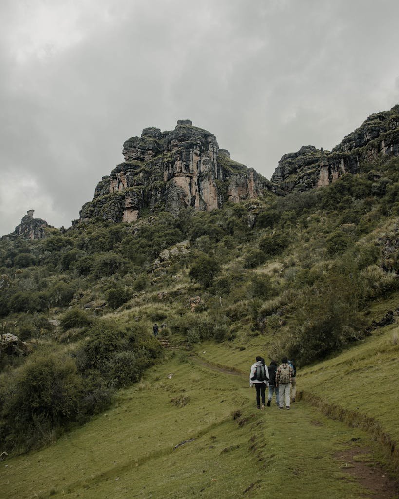 Explore the scenic trail leading to Waqrapukara ruins in Cusco, Peru, amidst lush mountainous landscapes.