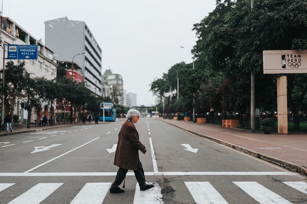 Senior man crossing a quiet city street in Lima, Peru, highlighting urban life.