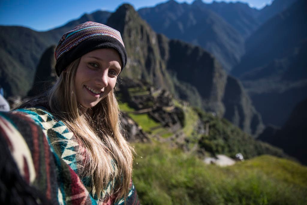 Woman in traditional attire taking a selfie at Machu Picchu, Peru.