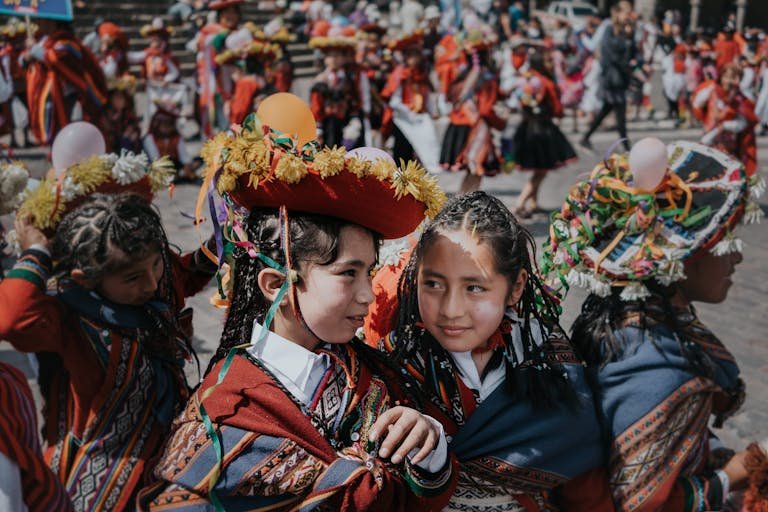 Children in colorful traditional costumes at a lively street festival in Cusco, Peru.